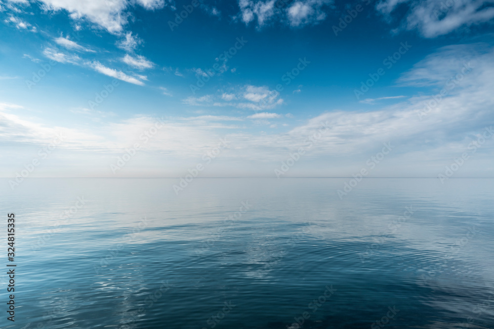 Beautiful white clouds on blue sky over calm sea with sunlight reflection, Harmony of calm water surface.