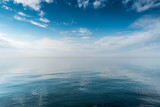 Beautiful white clouds on blue sky over calm sea with sunlight reflection, Harmony of calm water surface.