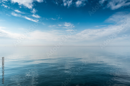 Beautiful white clouds on blue sky over calm sea with sunlight reflection, Harmony of calm water surface.