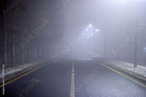 Misty road at night. Empty night road with dense fog. Dangerous driving conditions.