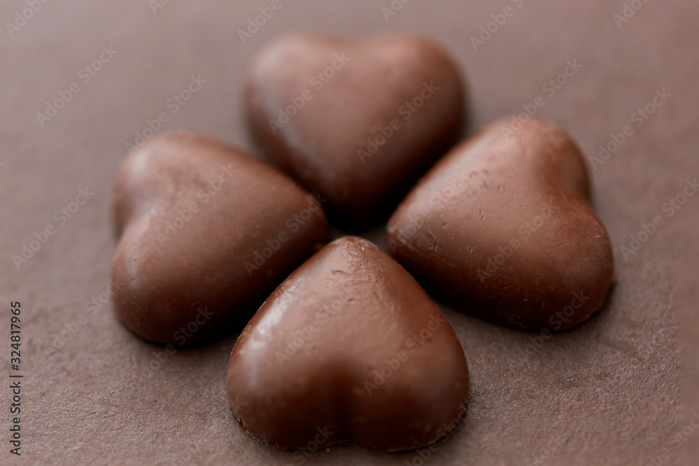 sweets, confectionery and food concept - heart shaped chocolate candies on brown background sweets, confectionery and food concept - heart shaped chocolate candies on brown background