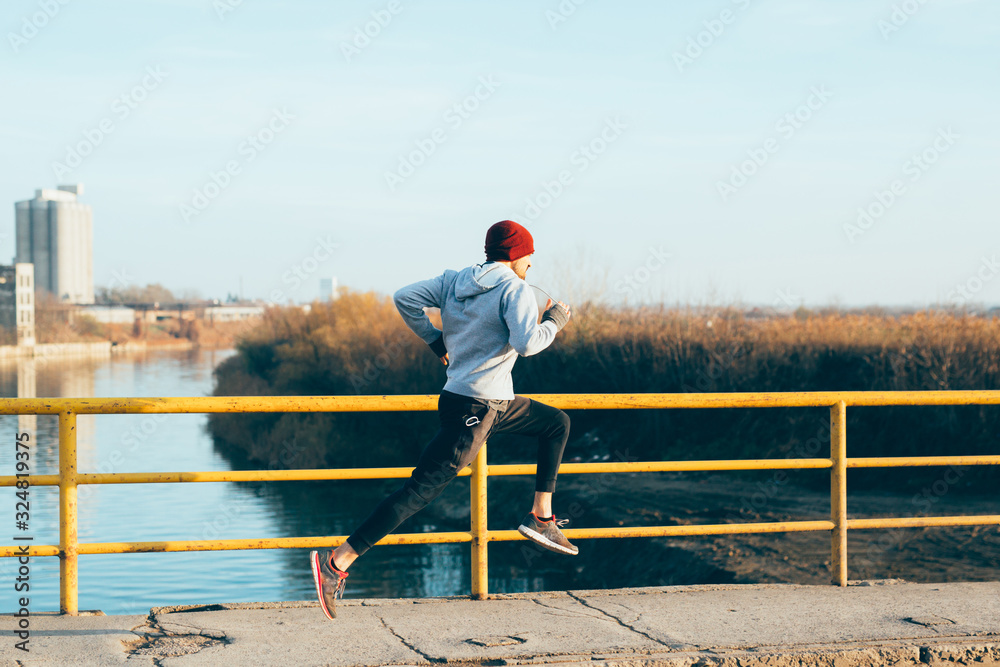young man jogging across bridge outdoors