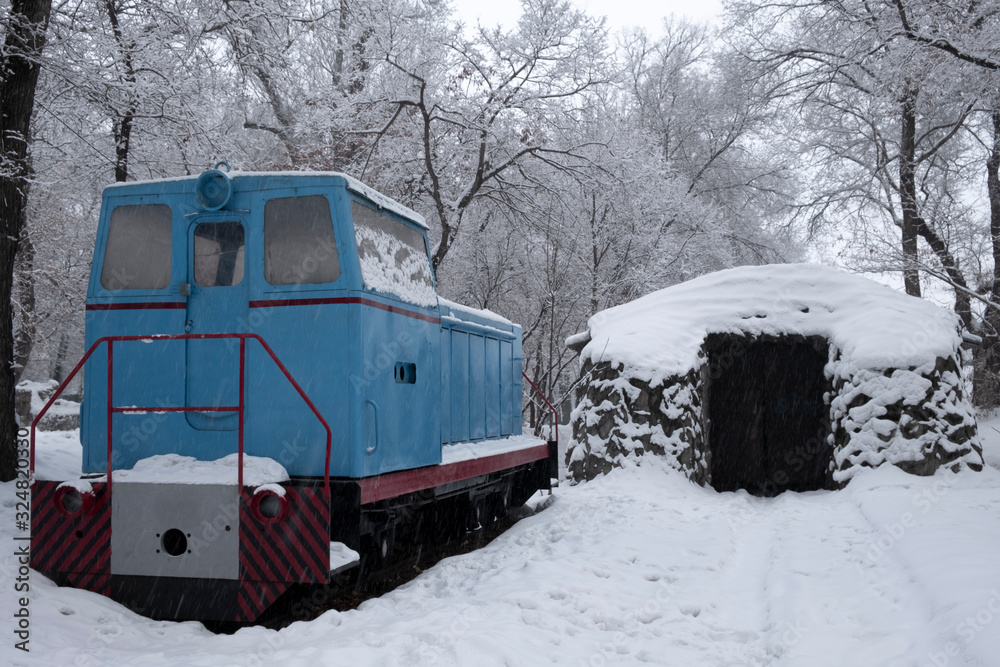 Abandoned narrow gauge locomotive. Narrow gauge locomotive under snow