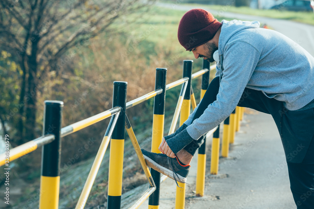 handsome young man jogging outdoor,tightening up shoelace handsome young man jogging outdoor,tightening up shoelace