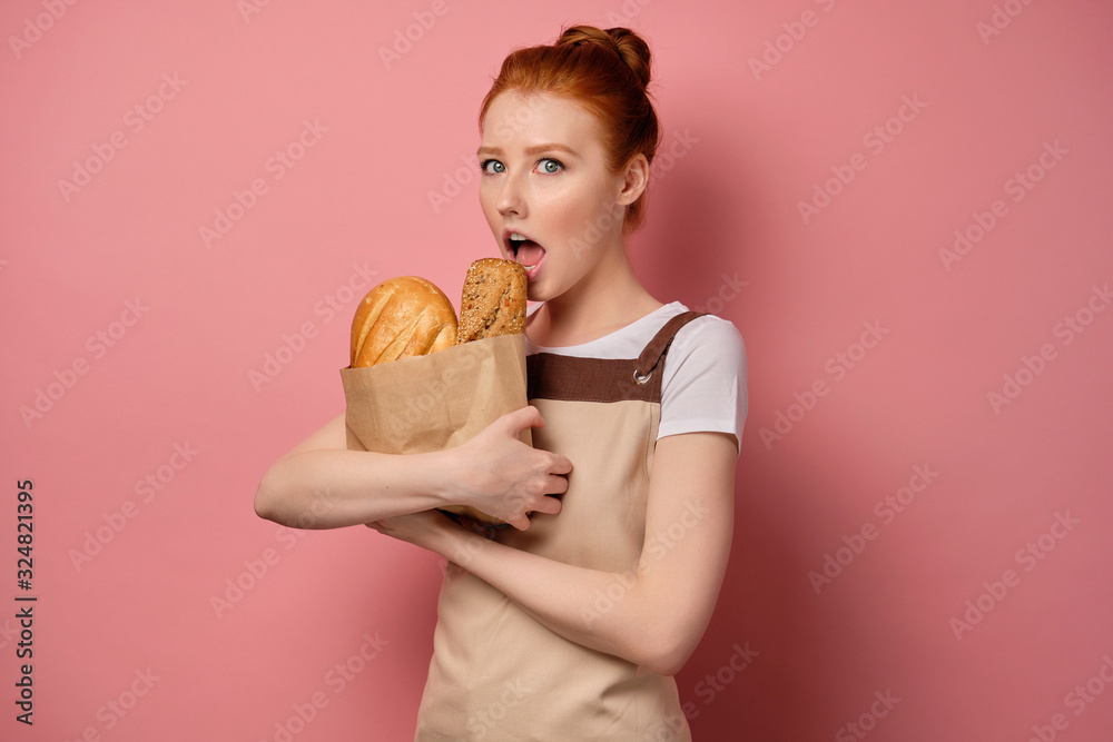 A cute red-haired girl with a high bun in a apron holding a bag of bread to herself and reaches out with open mouth A cute red-haired girl with a high bun in a apron holding a bag of bread to herself and reaches out with open mouth