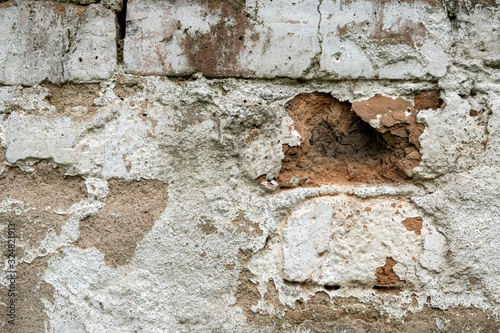 Old damaged brick wall with plaster background texture.