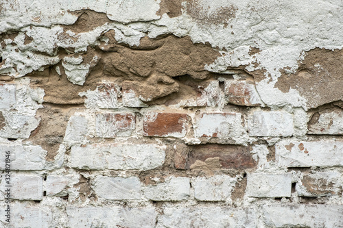 Old damaged brick wall with plaster background texture.