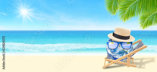 Summer Vacation Concept   Blue planet earth laying relax on beach chair on sand beach with beautiful seascape view in background.  Elements of this image furnished by NASA. 