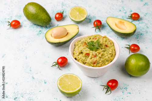 Fresh homemade hot guacamole sauce with ingredients on light background top view