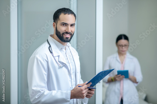 Dark-haired male and female doctors standing in the room