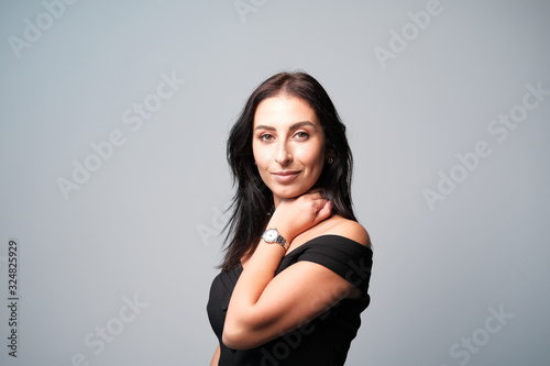 A large portrait of a middle-aged woman (30-35 years old) with dark hair and brown eyes in a black dress on a light background.