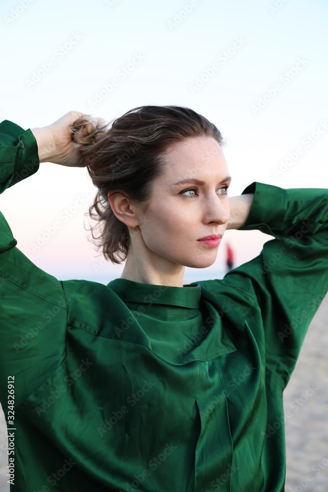 Young beautiful woman wearing green top and posing on the beach. Outdoor. Young beautiful woman wearing green top and posing on the beach. Outdoor.
