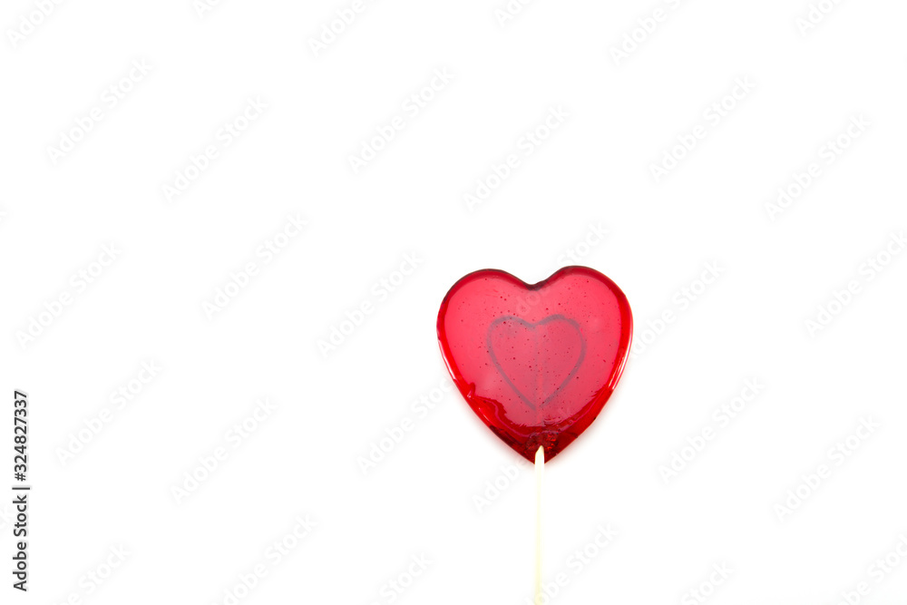 Sweet lollipop in the form of a heart of red-transparent color on a wooden stick on a white isolated background. Love and feelings in candy. Sweet lollipop in the form of a heart of red-transparent color on a wooden stick on a white isolated background. Love and feelings in candy.