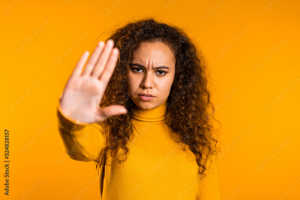 No, never, pretty curly woman disliking and rejecting gesture by stop palm sign. Portrait of young successful confident girl isolated on yellow background. No, never, pretty curly woman disliking and rejecting gesture by stop palm sign. Portrait of young successful confident girl isolated on yellow background.