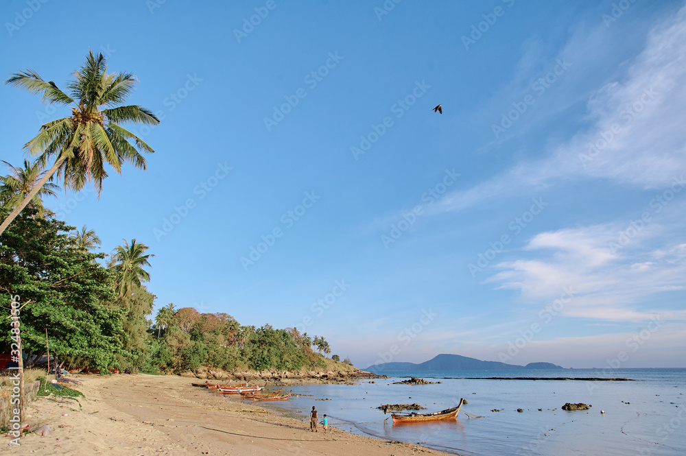 Fototapeta premium Landscape with tropical beach, coconut palm trees and traditional longtail boat. Phuket Island, Thailand.