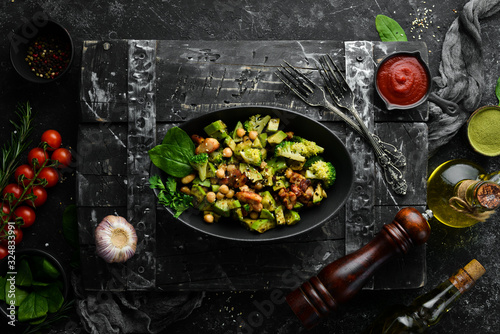 Healthy avocado salad, chickpeas, broccoli and chicken, in a black stone plate. Top view. Free space for your text.