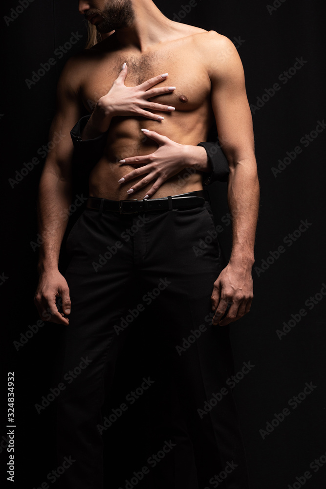 cropped view of young woman touching sexy man isolated on black
