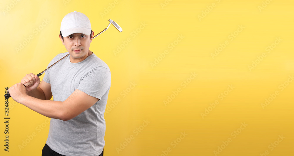 Golf Player Asian man in taking a swing, isolated on yellow background in studio With copy space.