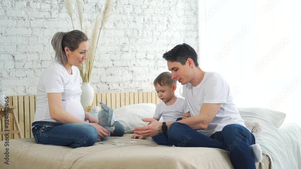 Beautiful Pregnant Mother and her Cute Little Son Giving High Five while Playing Training Cards with Father. Family of Three Having Fun at Home. Happy Family, Motherhood, Childhood and People Concept Beautiful Pregnant Mother and her Cute Little Son Giving High Five while Playing Training Cards with Father. Family of Three Having Fun at Home. Happy Family, Motherhood, Childhood and People Concept