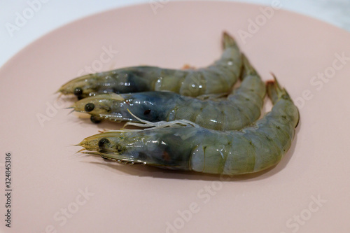 three raw prawns on a pink plate photo