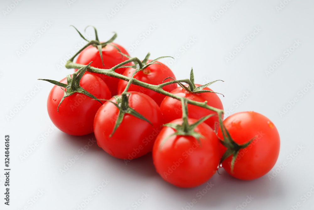 Beautiful red tomatoes on a green branch on a gray background. Selective focus. Vegetable