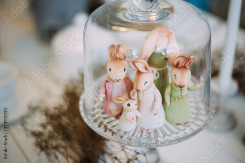 Incredibly cute family of toy rabbits on a glass tray among the decor and plants. Easter family holiday concept.