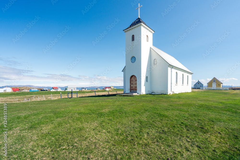 The local church and worlds smallest library in Flatey island in Iceland, the city of Flatey in the background. Religion, traveling and architecture concept