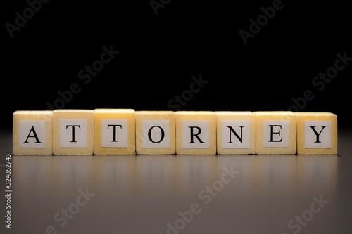 The word ATTORNEY written on wooden cubes isolated on a black background...