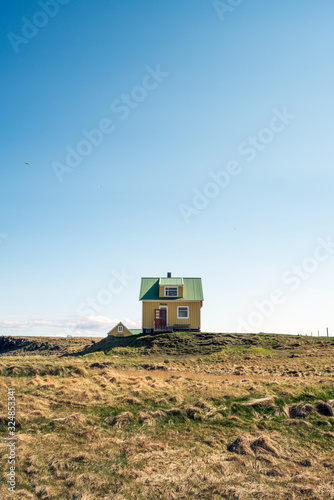 Yellow house on Flatey Island in Iceland just outside Stykkisholmur and the Westfjords. Blue sky and sunny weather. Explore and traveling concept. Vertical shot