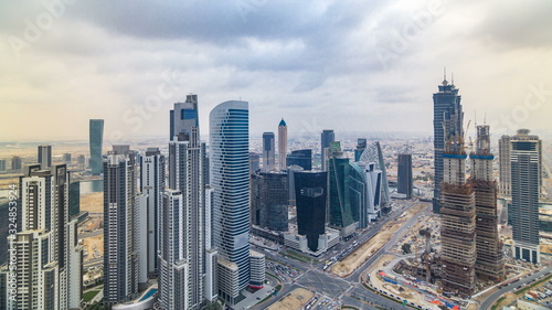 Dubai's business bay towers before sunset timelapse. Rooftop view of some skyscrapers and new towers under construction. © neiezhmakov
