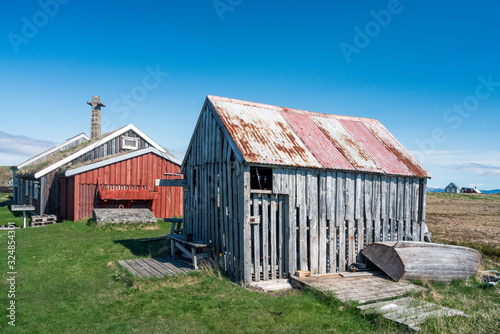 Old and weathered building on Flatey in Iceland. Factory pipe in the background. Blue sky during springtime