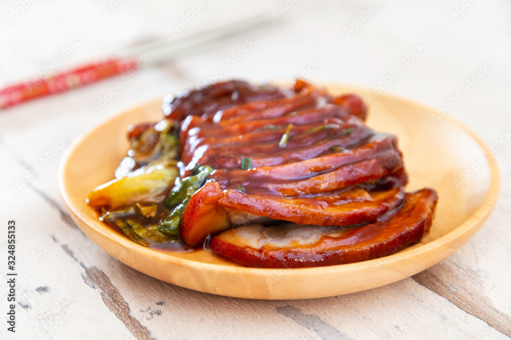 Chinese lacquered pork slices with its caramelized sauce prepared for eating in a wooden plate