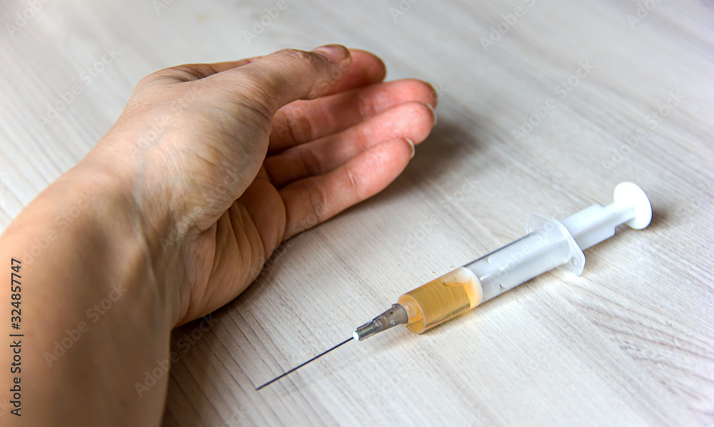 syringe with an injection in a female hand close-up, drug addiction topic, treatment of diseases, vaccinations and relief of symptoms of the disease syringe with an injection in a female hand close-up, drug addiction topic, treatment of diseases, vaccinations and relief of symptoms of the disease