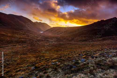 Beautiful valley with water reservoir in Mourne Mountains at golden hour and dramatic sunset. Mourne Mountains, highest range in Northern Ireland