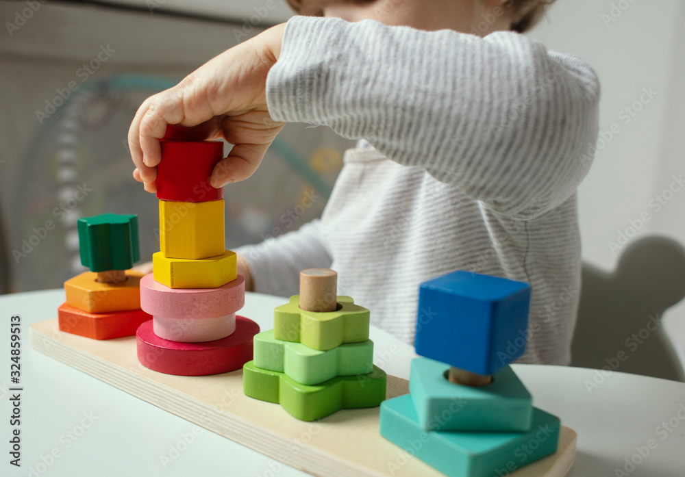 Beautiful toddler play with a wooden toys at home. Toddler play with a color educational toy. Child play at the table in the baby room. Child development. Funny baby. Lifestyle. Beautiful toddler play with a wooden toys at home. Toddler play with a color educational toy. Child play at the table in the baby room. Child development. Funny baby. Lifestyle.