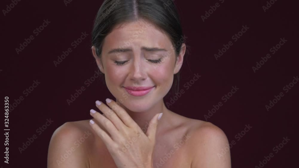 A nice young woman is crying with happiness isolated over dark red background A nice young woman is crying with happiness isolated over dark red background