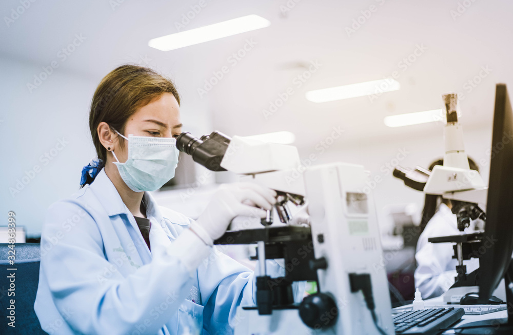 medical technician look at the microscope  in medical laboratory