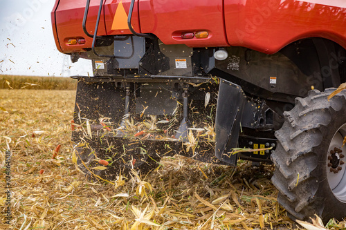 Closeup of chaff spreader on combine harvester harvesting cornfield. Corn trash of cobs, stalks and debris thrown from rear of combine photo