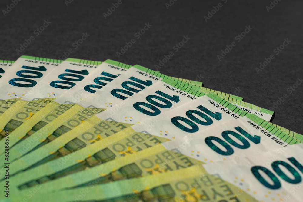 Obraz premium Money on a dark gray background. A fan of one hundred euro banknotes. Bill money currency. Cash note. Selective focus.