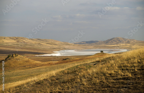 Fototapeta Naklejka Na Ścianę i Meble -  Beautiful sunny view of white desert lake with salt water among yellow fields at autumn time, south of Georgia
