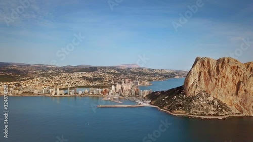 Flying over the sea next to a large rock. Residential houses in the touristic town of Calp in Alicante Spain