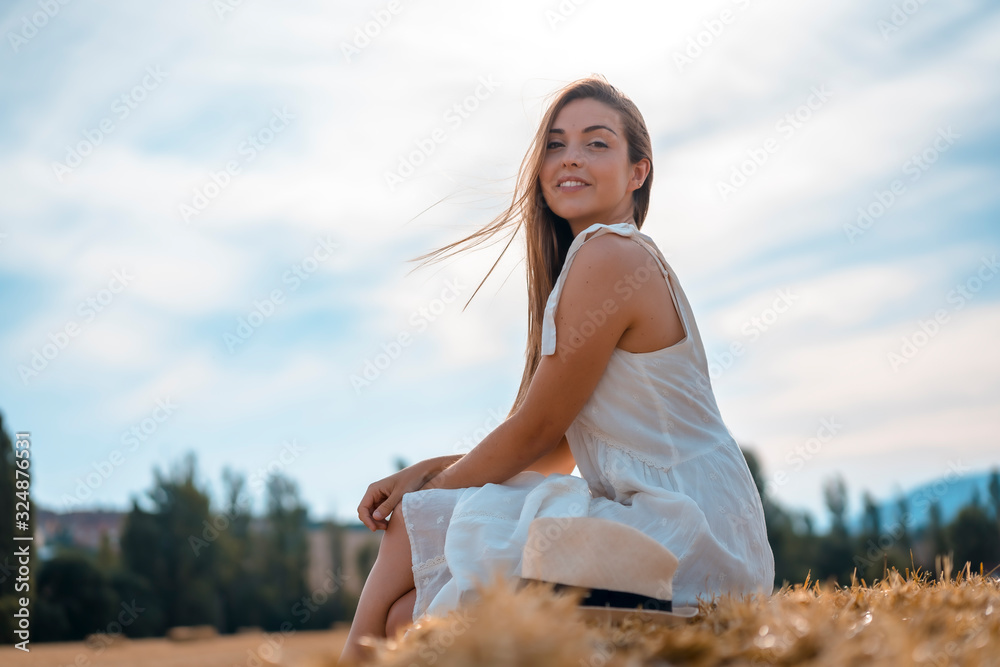 Rural lifestyle, a young blond caucasian farmer sitting in a straw field looking to the right Rural lifestyle, a young blond caucasian farmer sitting in a straw field looking to the right