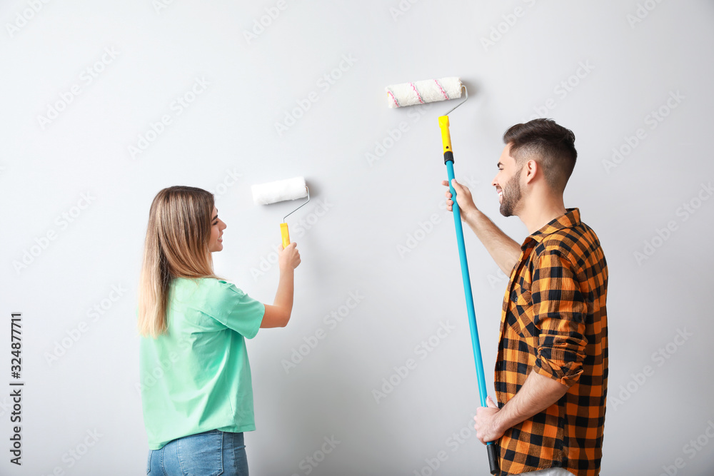 Young couple painting wall in new apartment