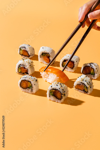 Chopsticks picking nigiri sushi out of maki rolls