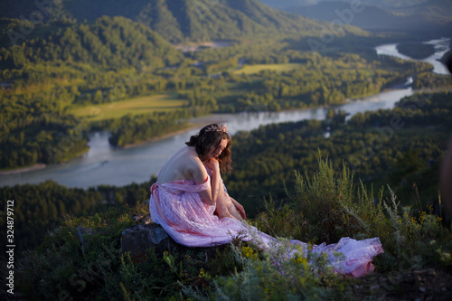 A girl in a pink dress with a long train. Bird s-eye. On the top of the mountain. Photosession in Altai