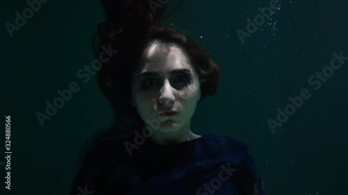 A brunette girl underwater looks at the camera and her hair develops. Mermaid and Nymph. Beautiful girl in the pool. Long hair.
