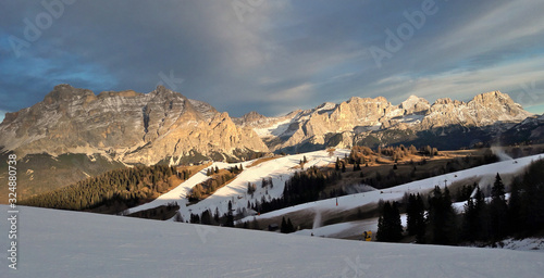 Wide dolomiten rocks view with many slopes and snow makers during winter golden sunset in Italy