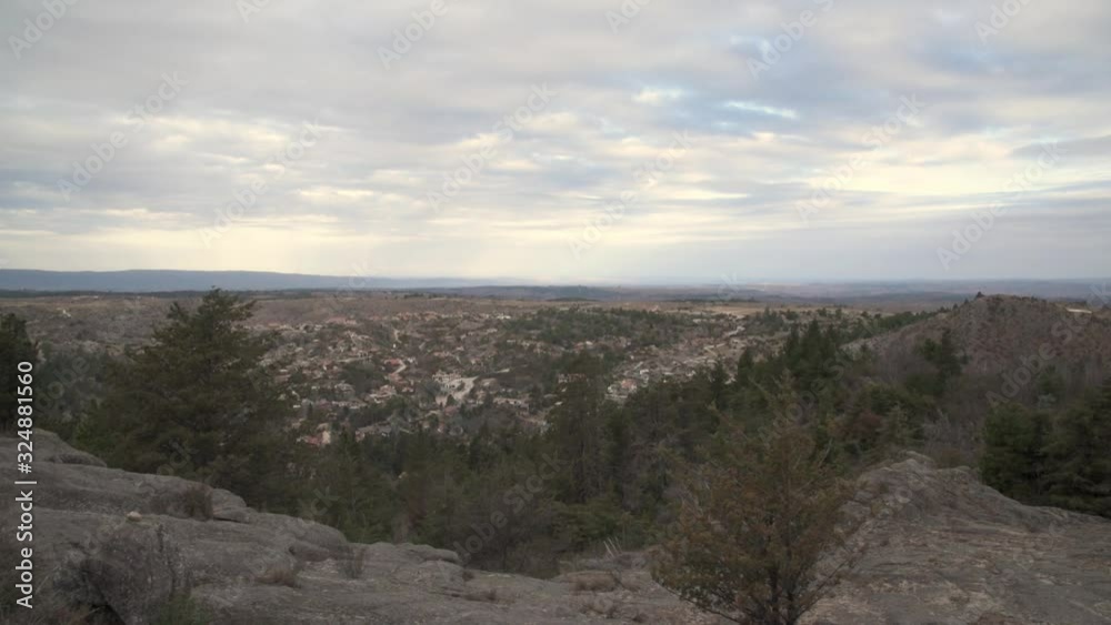 Time Lapse from the top of a mountain to a landscape of a valley with a Little pedestrian town surrounded by trees with movements of the clouds on a gray day Time Lapse from the top of a mountain to a landscape of a valley with a Little pedestrian town surrounded by trees with movements of the clouds on a gray day