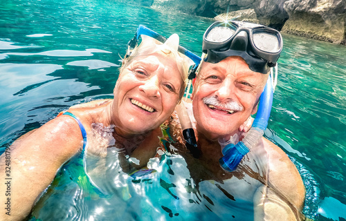 Happy retired couple with scuba mask taking selfie at tropical excursion - Boat trip snorkel experience in exotic scenarios - Elderly concept with active seniors traveling around world - Bright filter © Mirko Vitali