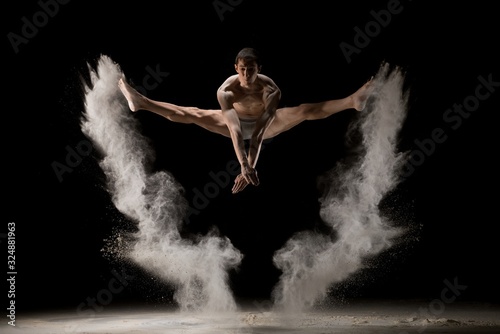 Male gymnast jumping in dust cloud view